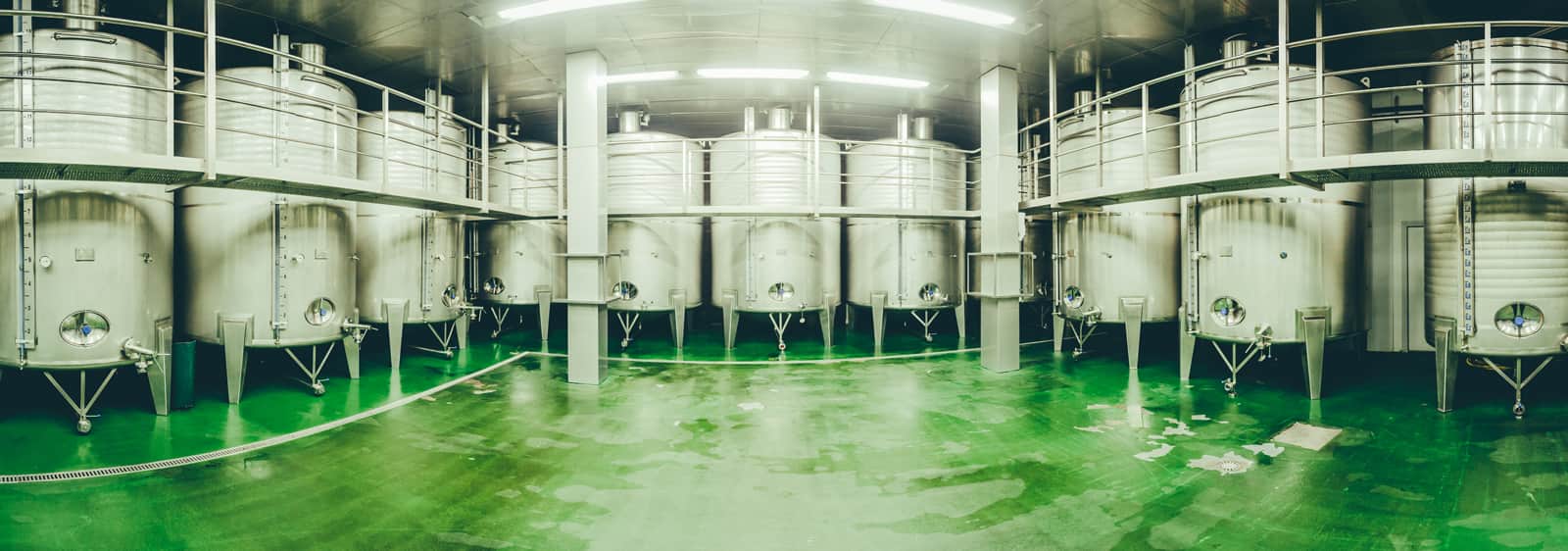 Panorámica de la bodega con barricas metálicas